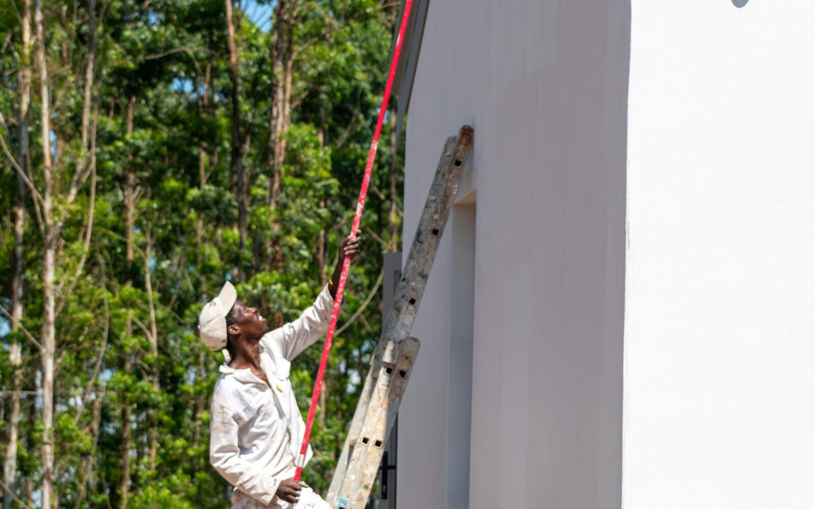 Painter working on a tall exterior wall.